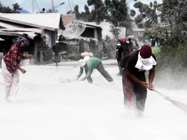 Moradores do distrito de Karo, na Indonésia, limpam as cinzas vulcânicas que se acumularam nas ruas, após o Monte Sinabung entrar em erupção - 24/05/2016