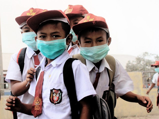 Crianças utilizam máscaras, ao irem para a escola, após a erupção do Monte Sinabung, no distrito de Karo, na Indonésia - 24/05/2016