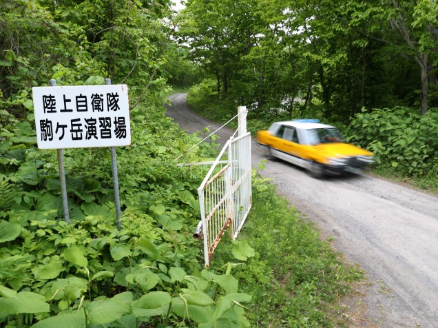Carro passa na entrada de uma área de exercícios militares na cidade japonesa de Shikabe em Hokkaido local onde o menino de sete anos desaparecido passou quase uma semana abrigado - 03/06/2016