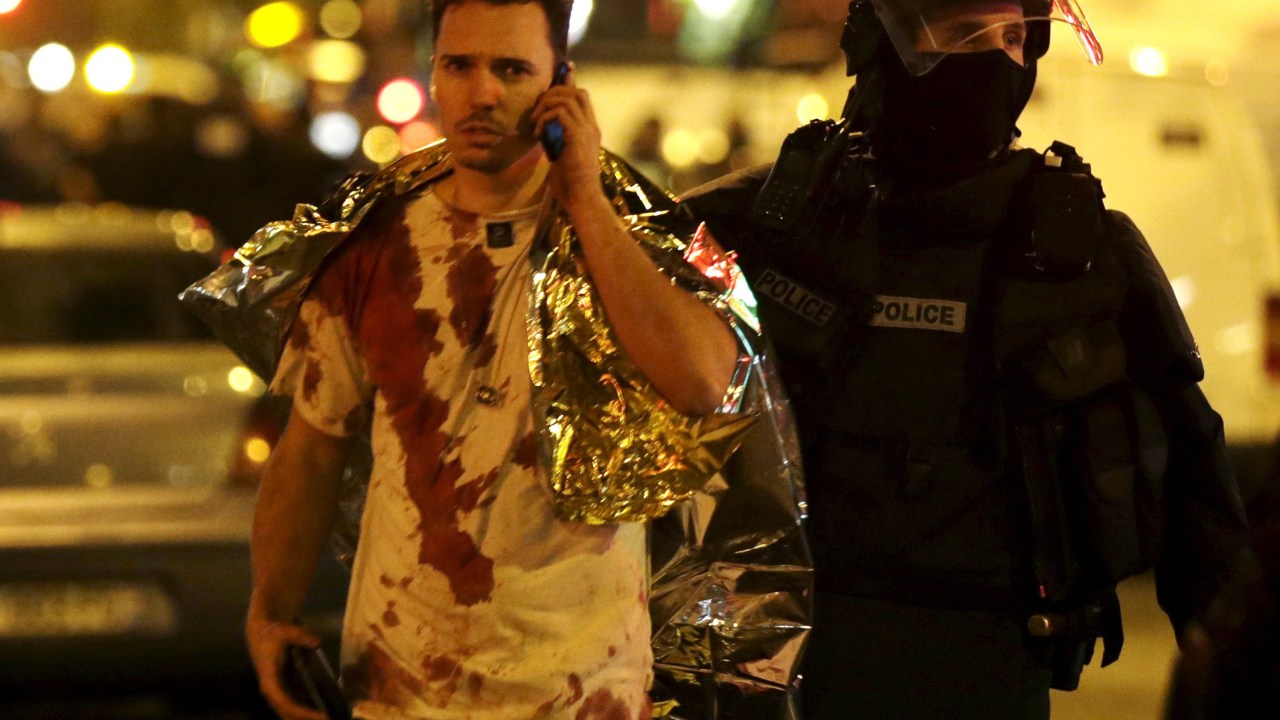 Policial auxilia uma vítima coberta de sangue perto da sala de concertos Bataclan após os ataques em Paris - 13/11/2015