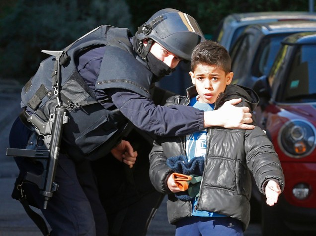 Policial fala com uma criança que estava a caminho de uma escola em Marselha, na França. Homens encapuzados e armados com fuzis dispararam contra a polícia - 09/02/2015