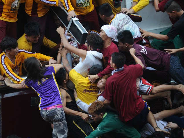 Fiéis católicos disputam posição em uma procissão para tocar a estátua de Jesus Cristo, conhecida como Nazareno Negro, em Manila, capital das Filipinas, nesta quarta-feira (09)