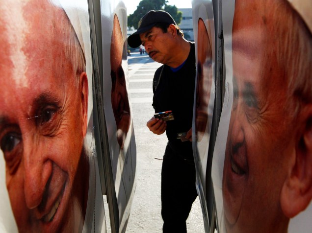 Homem observa telefone público, com fotos do Papa Francisco, na cidade de Tuxtla Gutierrez, no México, nesta segunda-feira (15)