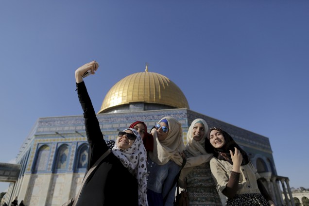 Mulheres palestinas tiram selfies em frente ao Domo da Rocha, santuário localizado em Jerusalém, durante o Ramadã