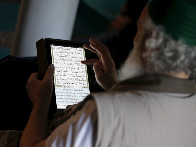 Muçulmano lê o Alcorão em árabe e alemão em seu tablet durante as rezas de sexta-feira em uma mesquita em Berlin, Alemanha
