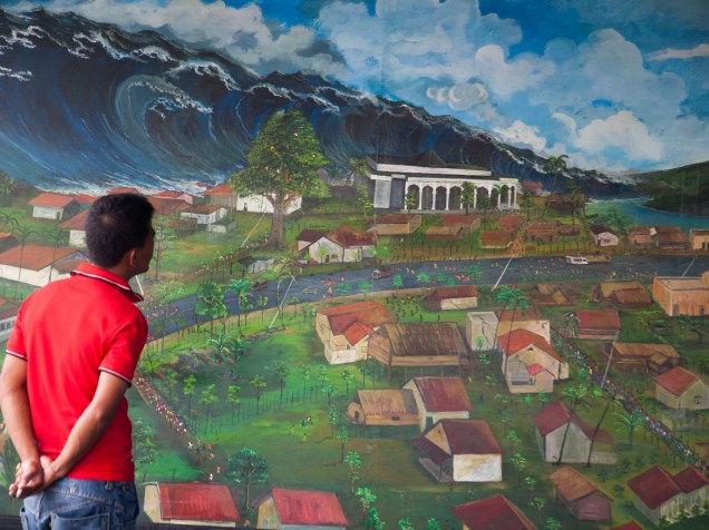 Sobrevivente observa pintura que retrata o desastre natural durante uma exposição em Lambada, na Indonésia