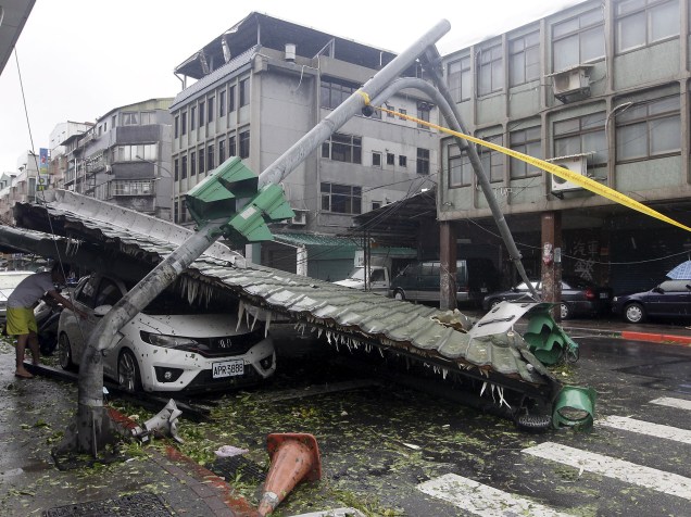 Homem olha carro esmagado devido aos estragos causados por um tufão em Taiwan