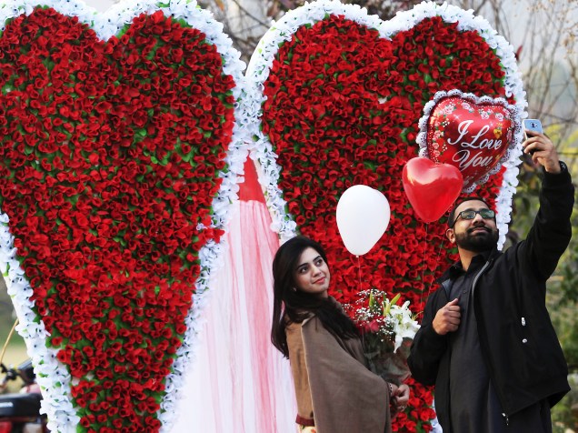 Casal tira uma selfie perto de um papel em forma de coração decorado em Islamabad, no Paquistão para celebrar o dia de Valentines Day, Dia de São Valentim