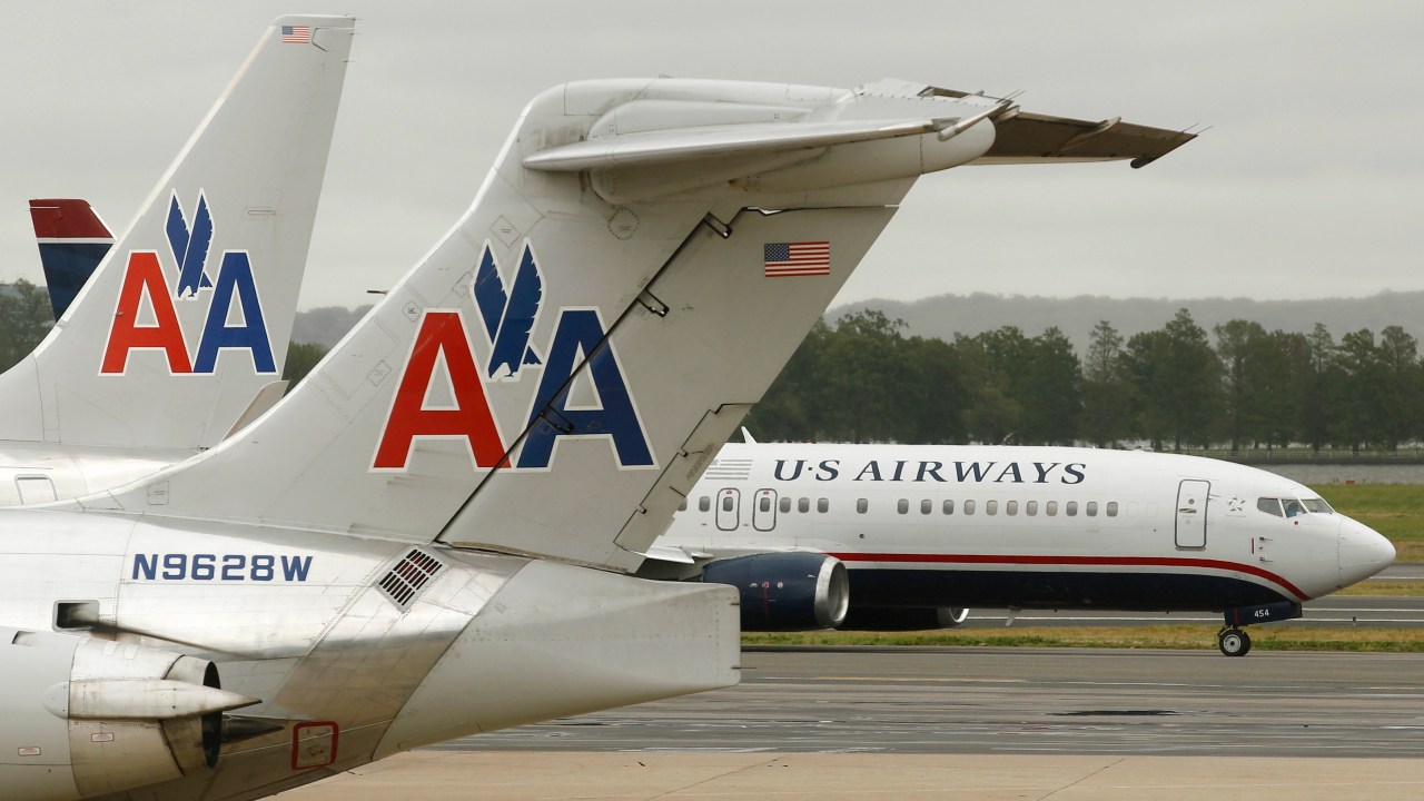 A US Airways plane and an American Airlines plane pass each other at Ronald Reagan National Airport in Arlington County, Virginia, in this file photo taken April 23, 2012. The unsecured creditors committee of bankrupt American Airlines parent AMR Corp has approved an $11 billion merger agreement with US Airways Group Inc, people familiar with the matter said on Wednesday. REUTERS/Kevin Lamarque/Files (UNITED STATES - Tags: TRANSPORT BUSINESS)