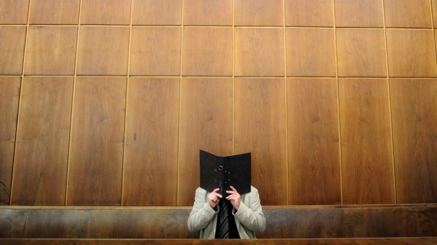O réu Andreas S., acusado de sequestrar um casal, cobre o rosto na sala do tribunal de Hanover, na Alemanha