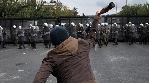 Homem grego atira garrafa contra policiais após o protesto resultar em conflitos na praça Sintagma