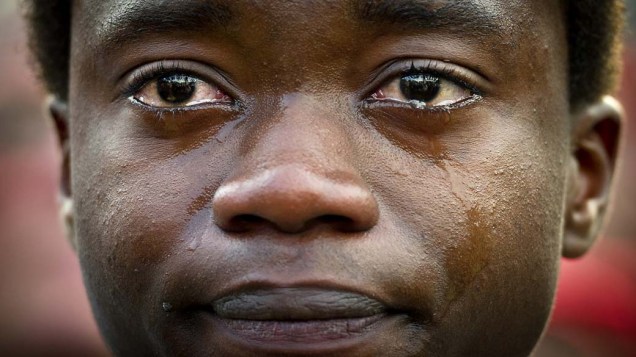 Jovem angolano chora durante passeata organizada para ajudá-lo a conseguir 55.000 assinaturas para que possa ficar em The Hage, na Holanda
