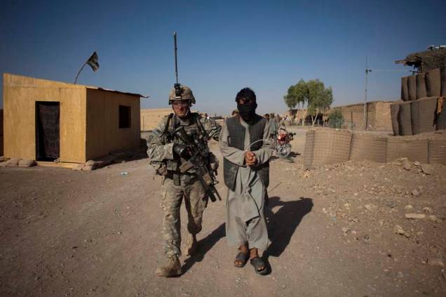 Um rebelde suspeito é levado para posto de combate americano por um soldado americano