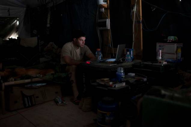 Soldado americano assiste a um filme em seu computador em barraca militar