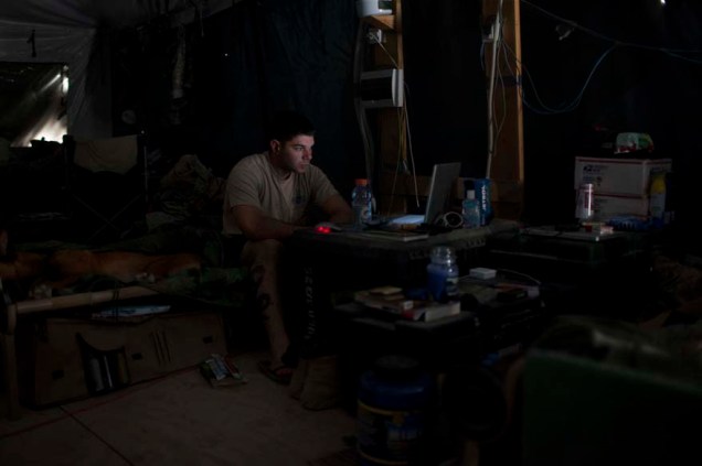 Soldado americano assiste a um filme em seu computador em barraca militar