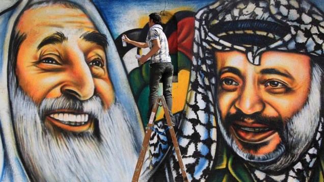 Artista palestino Mohammed al-Dairi pinta mural com ex-líder do Hamas, Sheikh Ahmed Yassin, e o ex-líder palestino, Yasser Arafat, em Gaza