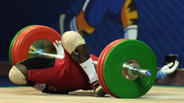 O atleta ganense Seth Degbe Fetrie cai durante prova de levantamento de peso nos Jogos da Comunidade Britânica, em Nova Deli, Índia