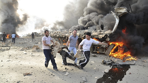 Imagem divulgada pela agência oficial síria mostra pessoas carregando um corpo queimado