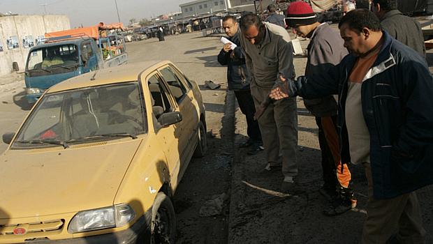 Moradores da região de Sadr, em Bagdá, observam carro danificado por explosões: ao menos 15 pessoas morreram em dois atentados registrados nesta quinta-feira