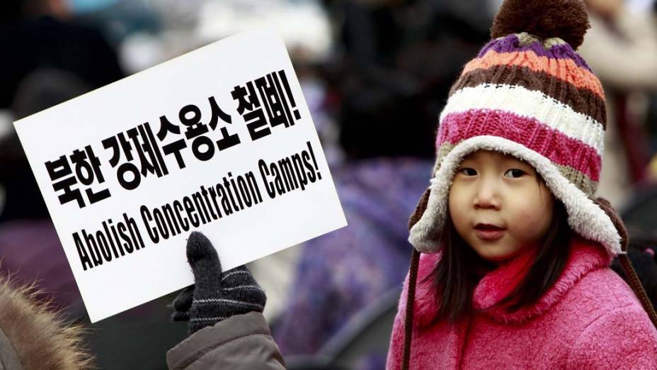 Em Seul, Coreia do Sul, garota participa de manifestação da Coalizão pela Liberação da Coreia do Norte ao lado de placa pedindo a abolição dos campos de concentração em Seul, Coreia do Sul