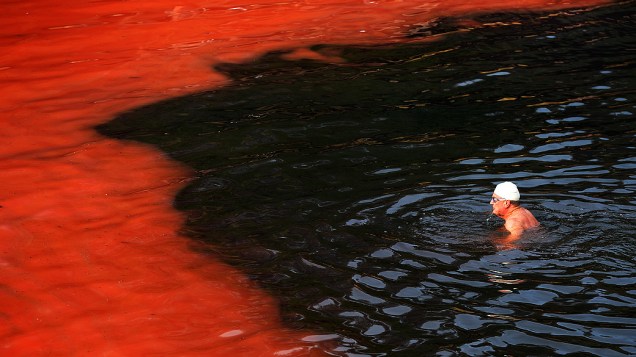 Banhista próximo à área do mar que ficou vermelha devido a uma alta proliferação de algas na praia de Clovelly, em Sydney, na Austrália, nesta terça-feira (27)