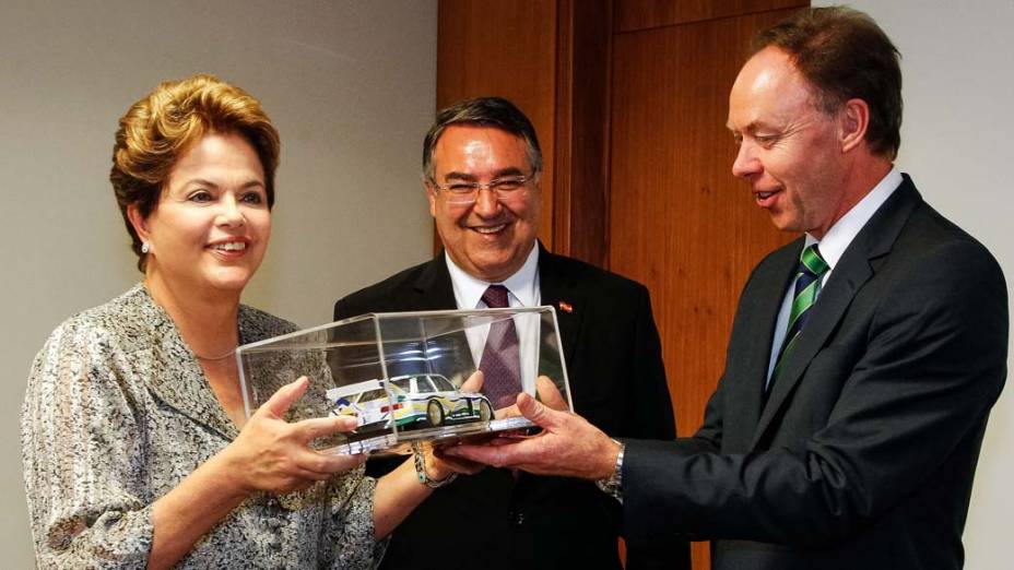 Felizes na foto - Presidenta Dilma Rousseff recebe miniatura de carro de Ian Robertson vice-presidente da BMW, observada pelo governador de Santa Catarina, Raimundo Colombo. A marca alemã anunciou a construção de fábrica no estado
