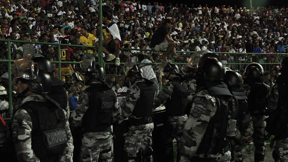 Policiais observam torcedores saltarem alambrado para escapar da arquibancada superlotada