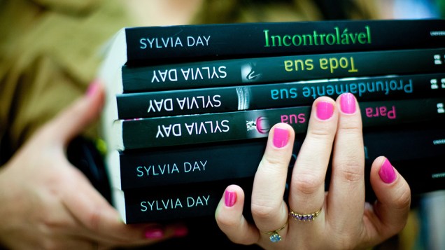 Mulher leva livros para a sessão de autógrafos com a escritora Sylvia Day, em São Paulo