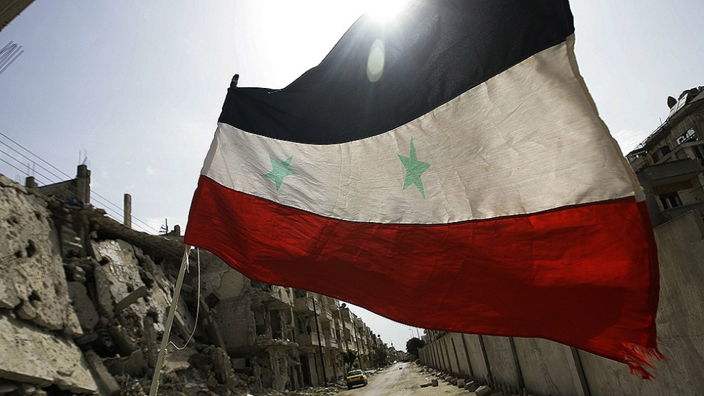 Bandeira tremula fora de um quartel militar no devastado bairro de Bab, em Homs, na Síria