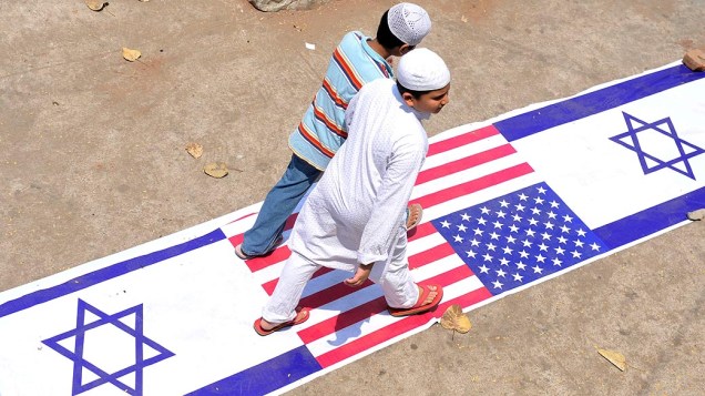 Garotos Muçulmanos caminham sobre as bandeiras de Israel e Estados Unidos durante a manifestação anti-Israel em Hyderabad, na Índia