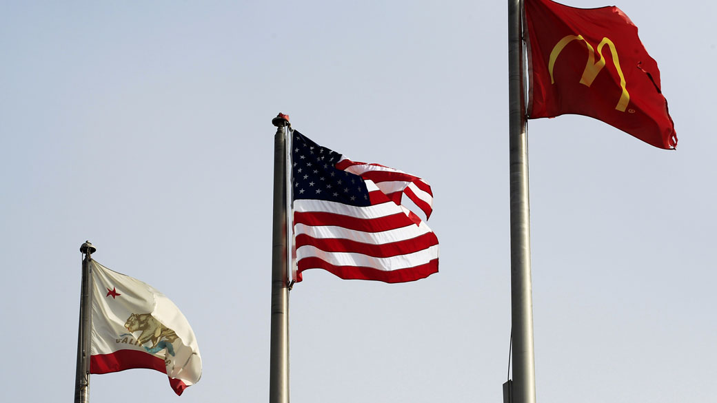 A bandeira dos Estados Unidos entre a bandeira do estado da Califórnia e uma bandeira do McDonalds, em San Ysidro, Califórnia
