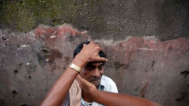 Homem recebe massagem em uma barbearia de rua em Mumbai, Índia