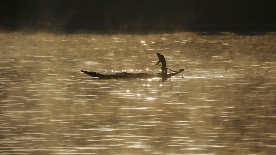 Homem pesca no rio Xinan na província de Anhui, na China