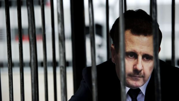 Manifestante com máscara de Assad posa atrás das grades