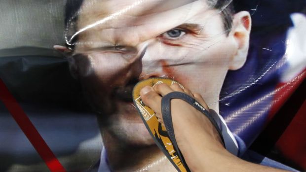 Um sírio que vive na Turquia protesta pisoteando a foto do ditador Bashar Assad