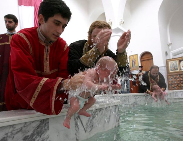Na Geórgia, sacerdote ortodoxo batiza criança. Cerca de 700 bebês participaram da cerimônia religiosa que teve o intuito de aumentar o número de frequentadores da igreja ortodoxa na região