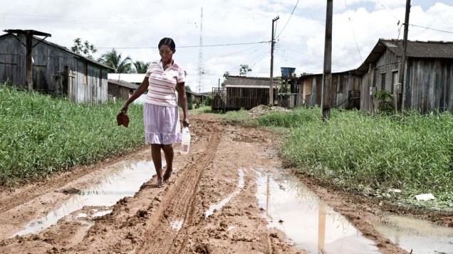 Maria Nazaré do Nascimento poupa os sapatos e suja os pés na rua sem asfalto e repleta de lama do bairro Boa Esperança, em Altamira