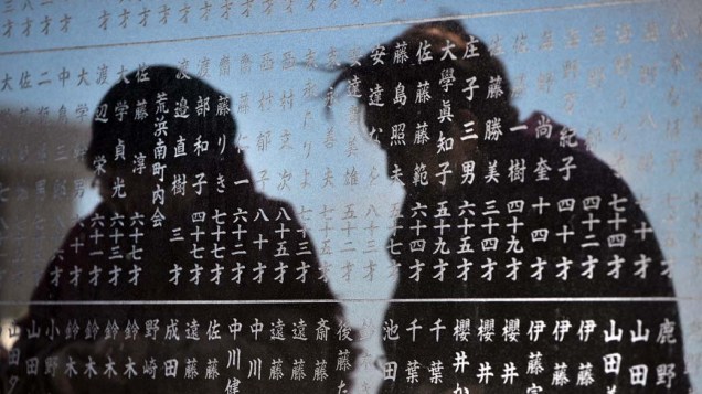 Mulheres prestam homenagem as vítimas do tsunami em monumento no distrito de Arahama em Sendai, Japão
