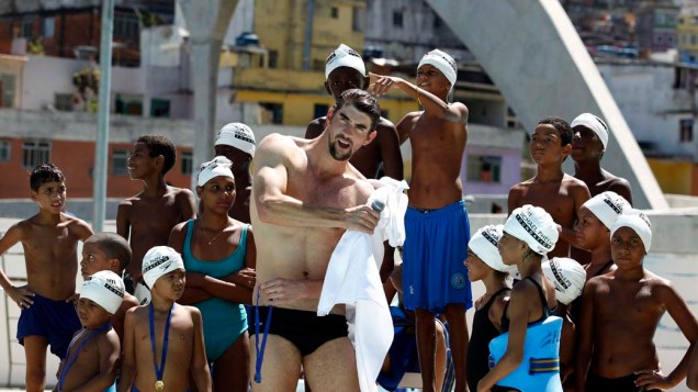 O nadador Michael Phelps posa com crianças durante visita ao Rio de Janeiro