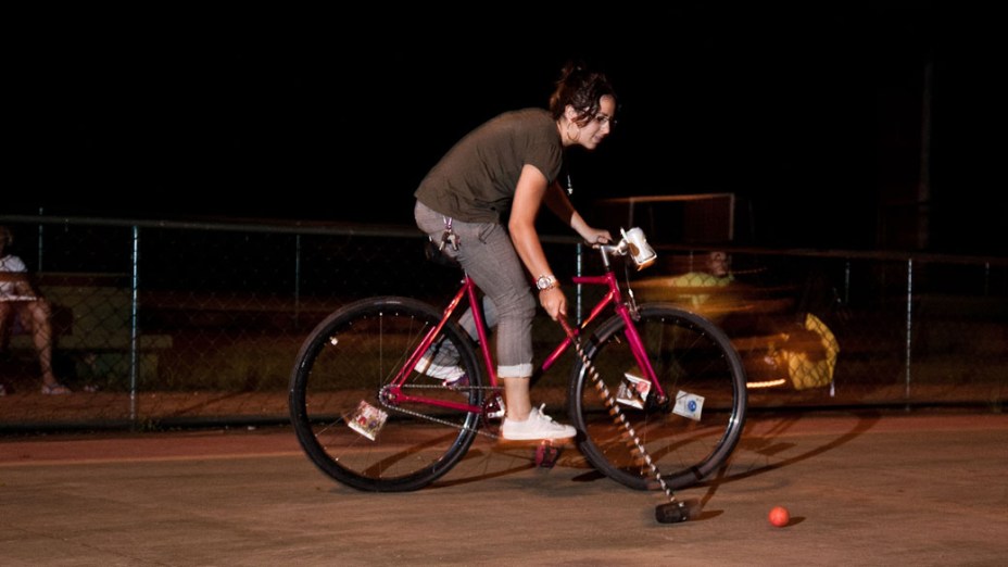 Jovem iniciante tenta dominar bolinha com taco, durante partida de Bike Polo, em São Paulo