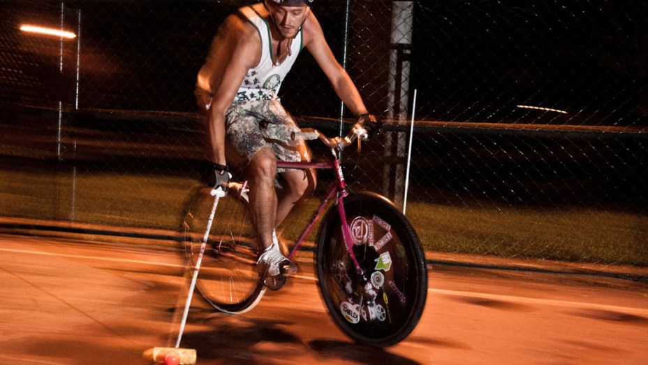 Entusiasta corre com a bola dominada durante partida noturna de Bike Polo, em São Paulo