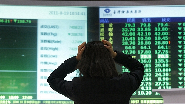 Mulher monitora quadro eletrônico de ações na Bolsa de Taipei, em Taiwan: Ásia afundou em perdas nesta sexta-feira ante temor de recessão global