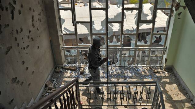 Policial tira foto dos destroços de um prédio, após ataque suicida em frente do edifício em Cabul