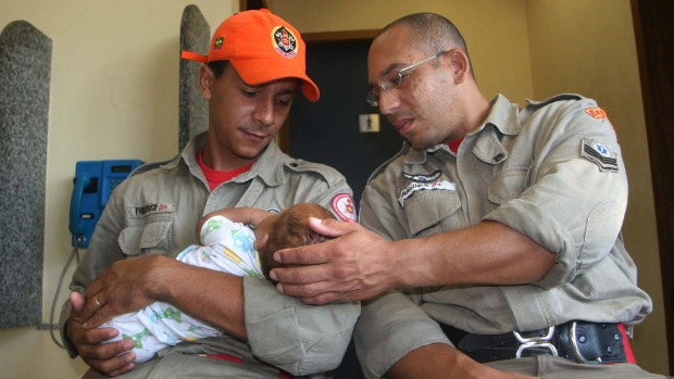 Bebê abandonado pela mãe com os bombeiros que o resgataram, em Santa Cruz: ela foi presa