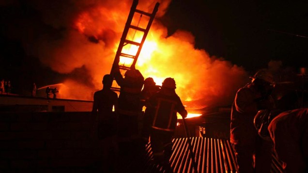 Bombeiros durante combate à incêndio em armazém de roupas e tecidos em Manila, Filipinas