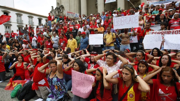 Mulheres e filhos de bombeiros se ajoelham em manifestação contra a prisão de 439 bombeiros