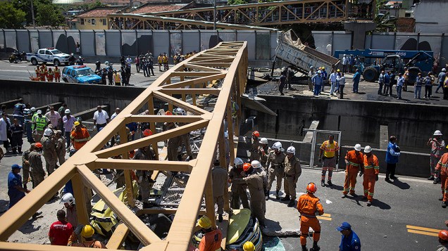 Homens trabalham para remover um corpo debaixo da ponte que desabou depois de ser derrubada por um caminhão, na Linha Amarela, no Rio de Janeiro