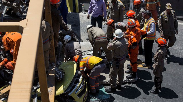 Homens trabalham para remover um corpo debaixo da ponte que desabou depois de ser derrubada por um caminhão, na Linha Amarela, no Rio de Janeiro
