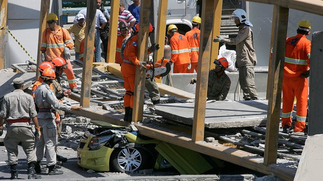 Homens trabalham para remover um táxi debaixo da ponte que desabou após ser derrubada por um caminhão, na Linha Amarela, no Rio de Janeiro