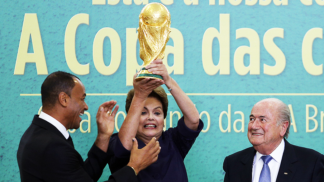 Presidente Dilma Rousseff levanta a Taça da Copa do Mundo, durante apresentação oficial pelo presidente da Fifa, Joseph Blatter, no Palácio do Planalto em Brasília